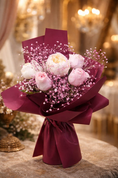 Peony and pink rose bouquet with pink baby's breath wrapped in rich burgundy paper